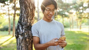 man standing outside in leisure clothes while holding a mobile phone
