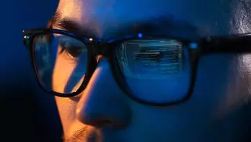close up of the eyes of a man wearing glasses looking at a computer screen