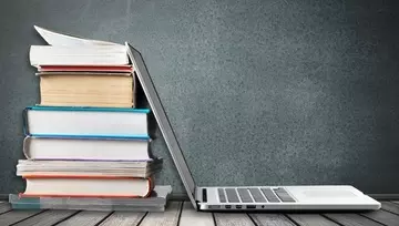 a stack of books with a laptop leaning up against them