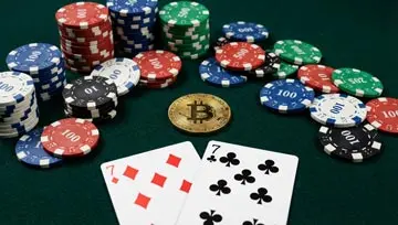 a bitcoin on a casino gambling table with casino chips and a pair of 7s 