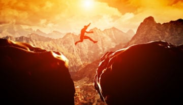 man jumping from rock to rock in the wild