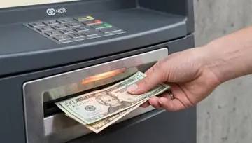 une main retirant de l'argent d'un distributeur automatique Retrait d'espèces