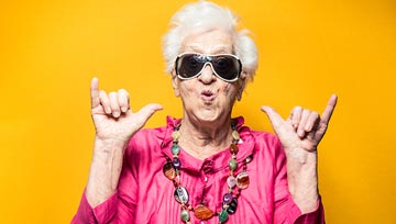 funky grandmother with sunglasses giving the "hang loose" sign with her hands.