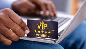 man with a laptop holding a VIP Member card