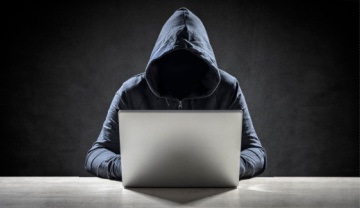 faceless man in a hoodie on a laptop