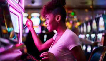 happy woman playing a slot machine in a real casino
