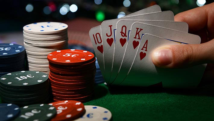 poker hand showing a royal flush with stacks of chips