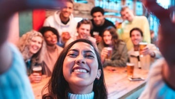 Millenial and Gen Z friends gather for a beer and take a group selfie