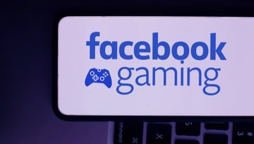 mobile phone with “Facebook Gaming” logo with a keyboard in the background