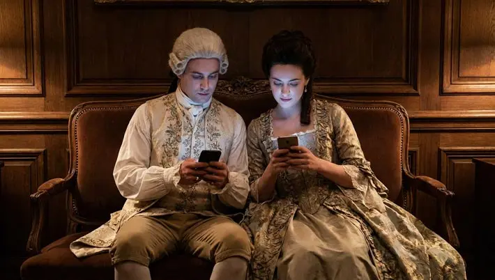 couple dressed in period clothes playing on mobile phones 