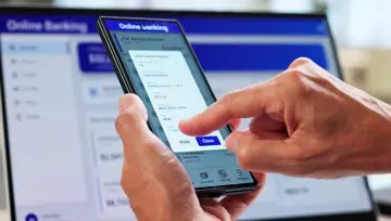 person holding a mobile phone with "online banking" displayed