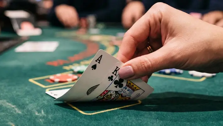 woman's hand picking up the corners of 2 cards that total 21 