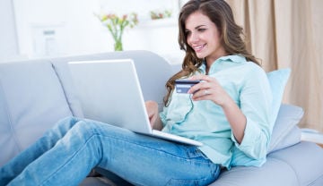 woman holding a credit card while on a laptop  