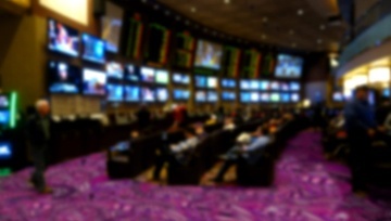 casino sportsbook screens on the wall with sportsbook betters sitting at their seats
