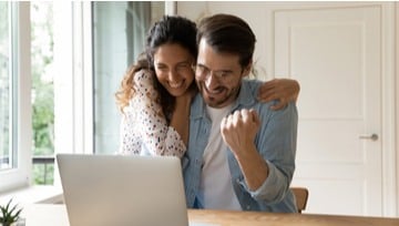 couple happy after winning a sports bet on their laptop