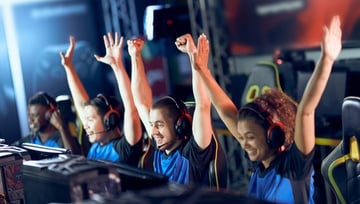 Esports team celebrating while sitting at their computers