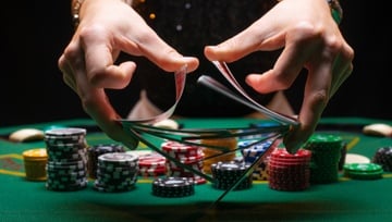 female dealer shuffling the cards on a poker table with chips all around