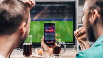 two friends doing sports betting on their phone and laptop