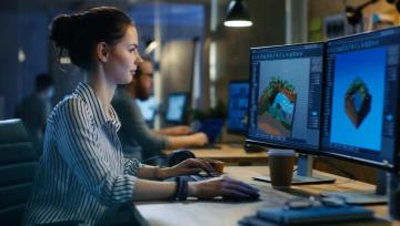Woman game developer working on 2 computer screens