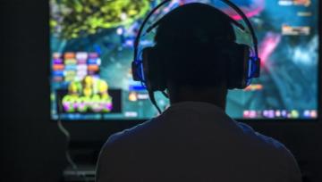 gamer sitting in front of a big screen playing a game