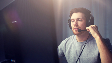 guy sitting by his computer playing streamed gaming content  