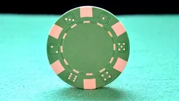a green gambling chip balancing on the table