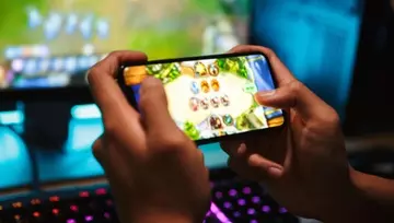 hands of a gamer playing a video game on his mobile device