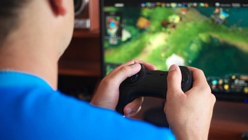 man playing eports on his screen with a gaming console in his hands