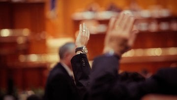 men holding up their hands as if voting in a committee meeting  