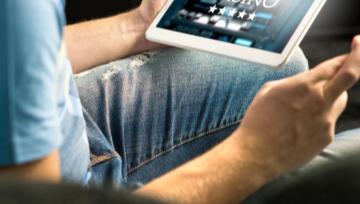 a person sitting playing online casino games on a tablet with his fingers crossed for good luck 