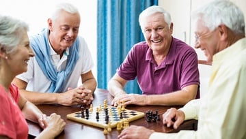 seniors sitting around watching two play a game of chess