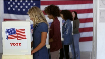 4 women lined up to vote with an American flag in the background